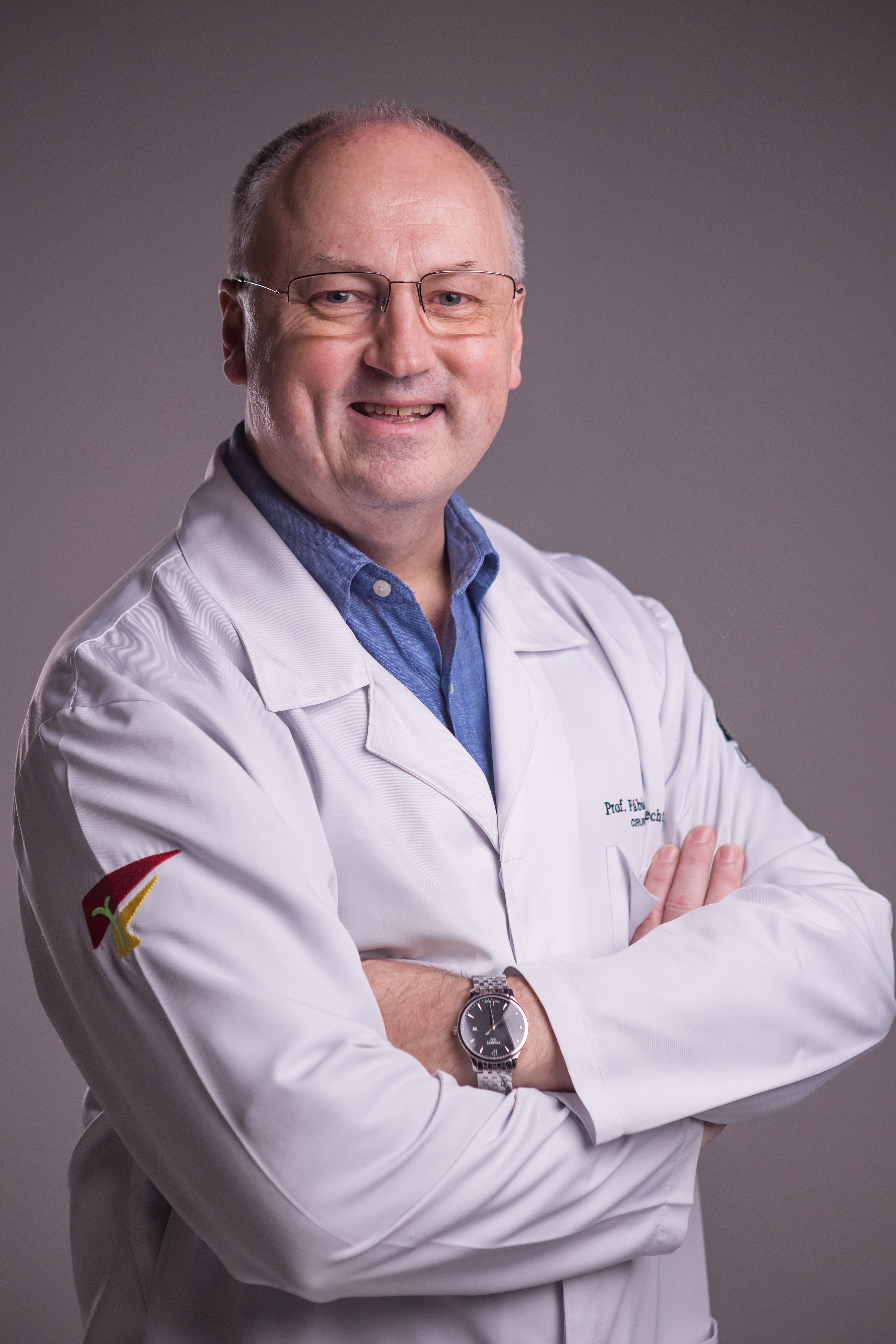 Dr. Fábio Luiz Waechter de jaleco, braços cruzados, sorrindo