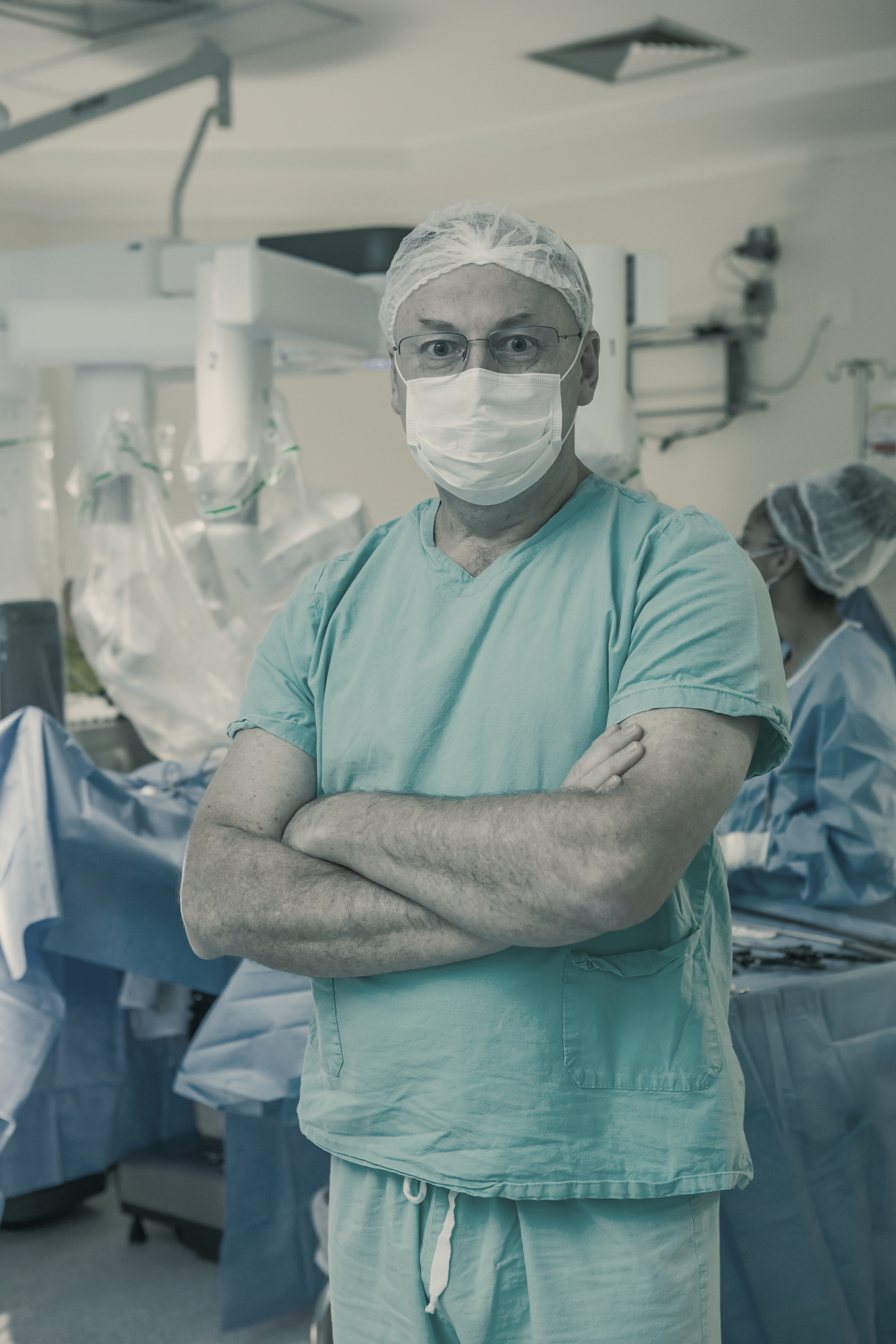 Dr. Fábio Luiz Waechter de braços cruzados no bloco, com a equipe de touca e máscara ao fundo